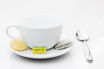 Green tea bag, cup and saucer with lemon wedge