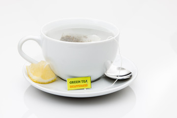 A cup of green tea on a saucer with lemon wedge