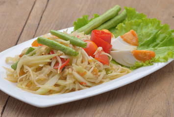 papaya salad, som tum and salted egg on wooden background