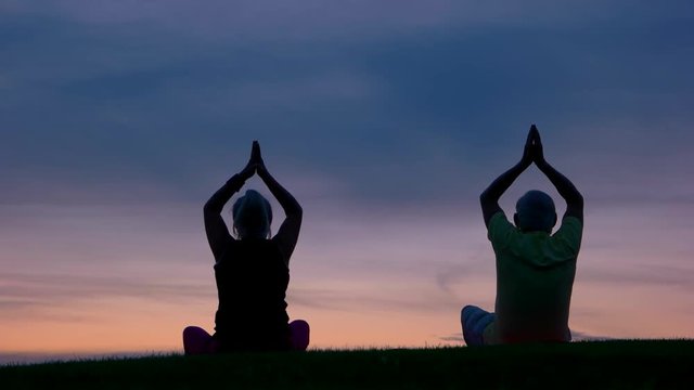 Couple doing yoga. People on sunset sky background. Strive to harmony. Way to peace and balance.
