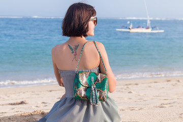 Fototapeta na wymiar Young slim sexy woman on the beach. Luxury handmade snakeskin in her hands.