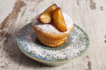 Fresh baked muffins with plums and powdered sugar on plate, delicious dessert