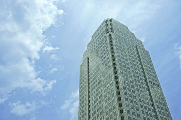 Perspective view to textured background of modern glass building skyscrapers over blue cloudy sky.