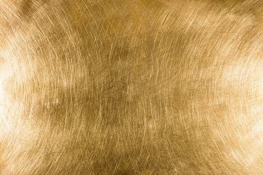 scratched industrial brass metal plate textured background pattern with light reflections