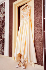 White luxury bridal dress is hanging on door at wall background