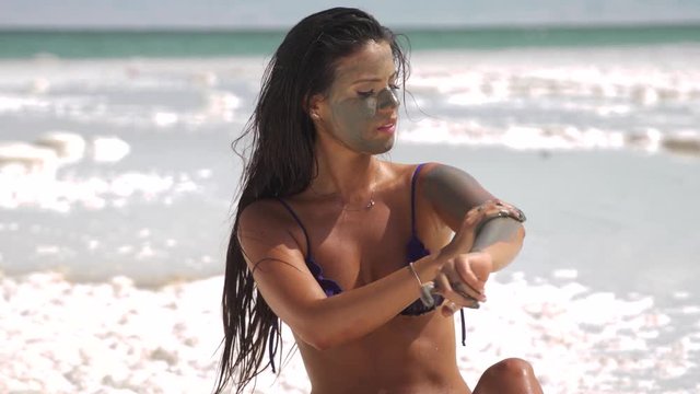 Beautiful girl rubs dead sea mud on the body.