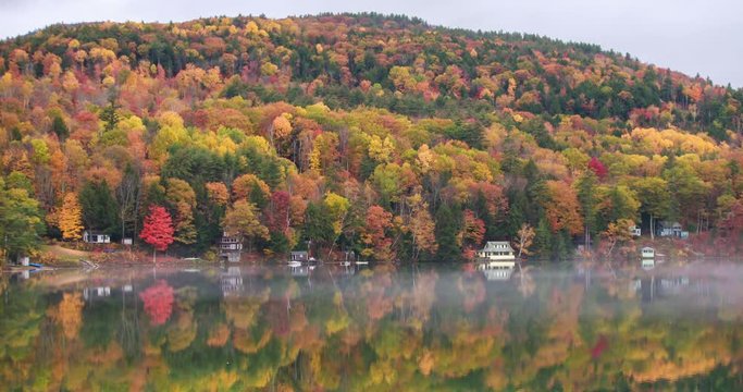 Fog moves over a lake near a mountain, timelapse.