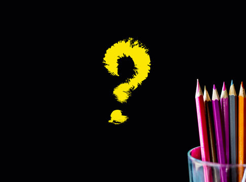 Color pencil on black background with word: Questions mark?