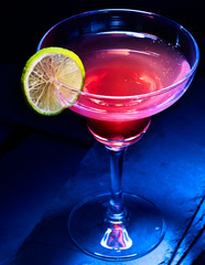 Obrazy na Szkle  Koktajl alkoholowy jagodowy z plasterkiem cytryny na czarnym tle. Koktajl alkoholowy w kieliszku martini.