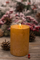 Fir branch in snow, lighted candle, cone on wooden background. Christmas theme