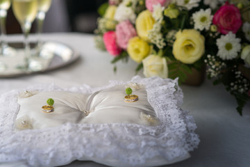 Wedding rings laying on white lace pillow.