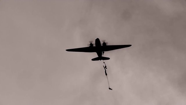 Low angle view of military aircraft dropping paratroopers