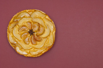 Whole tarte Tatin apple pear tart isolated on claret background