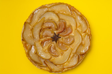 Whole tarte Tatin apple pear tart isolated on yellow background