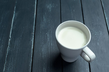 Glass of milk on table on blurred natural background