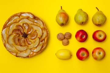 Whole tarte Tatin apple tart with fruits on yellow background