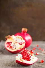 Broken ripe pomegranate on the background of the old wooden tabl