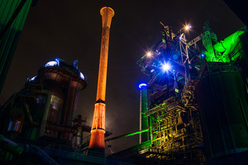 illuminated chimney of industrial plant by night, duisburg