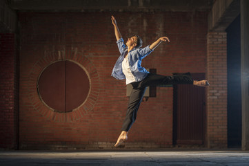 Fototapeta premium Young graceful dancer doing ballet jump outdoors
