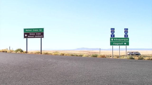 Signage on Interstate 40 in Arizona, Albuquerque, Flagstaff and Meteor Crater Natural Landmark, Car drives by.