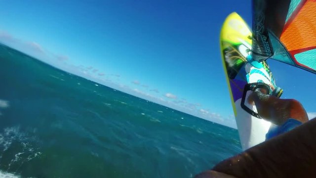 POV windsurfer jumping off blue ocean wave, extreme sport