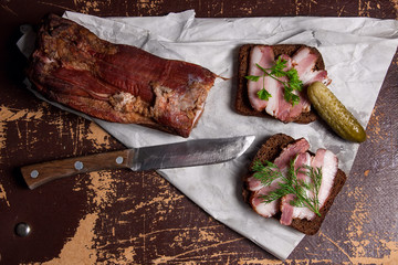 Smoked bacon with rye black bread and several pickles on the pac