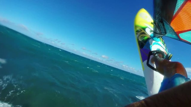 POV windsurfer jumping off blue ocean wave in slow motion, extreme sport