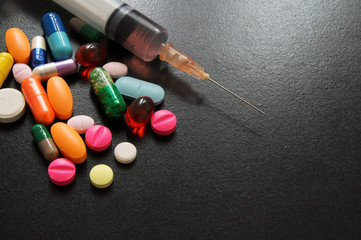 Drugs and syringe on wooden table with room for text, medical concept.
