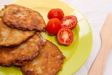 Potato pancakes with meat and tomatoes on green plate in Belarus