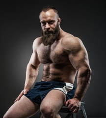 Fototapeta na wymiar Portrait of strong bearded man with perfect abs, pecs shoulders,
