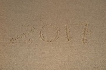 Fototapeta na wymiar 2017, a message written in the sand at the beach.