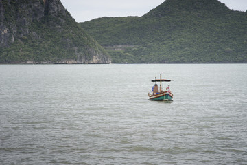 traditional fishing boat laying on the sea with big and long mountain in background.cloudy sky.filtered image.selective focus