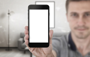 Guy show black smart phone with isolated screen for app presentation. Mobile mockup. Living room interior in background.