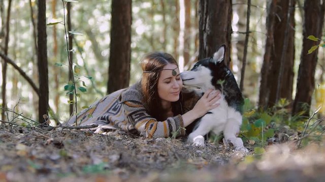 Smiling young woman lying in the forest and having a moment of tenderness with her darling pet