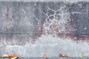 Gray, old stony asphalt texture background with small autumn leaves in the foreground. Close up stairs with strange formations. Focus point in the middle of photo.