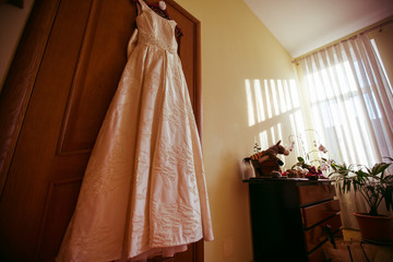 Classy beige dress hangs from the wooden door