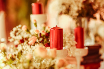 Wine red candle stands over the white bouquet on the dinner tabl
