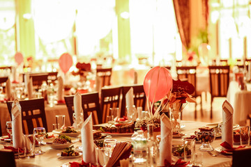 Flowerpots with red balloons stand on the festive served dinner