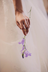 gentle hand of the bride holding delicate purple flower