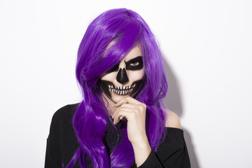 Young woman with gothic skeleton makeup purple wig over white background