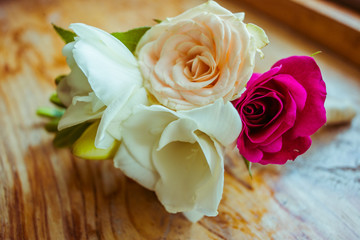 Pretty boutonniere made of white and pink flowers lies on the wo