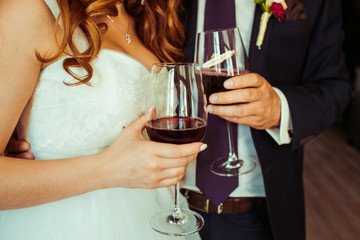 Bride and groom hold in their hands glasses with wine