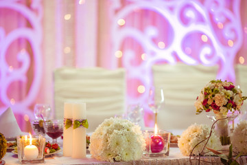 Wedding dinner table decrated with white candles and flowers