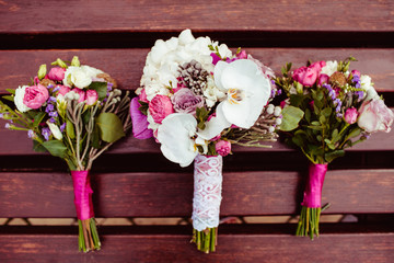 White and pink wedding bouquets lie on the wooden banch