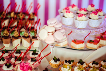 Naklejka premium White macaroons lie on the glass vase among other sweets