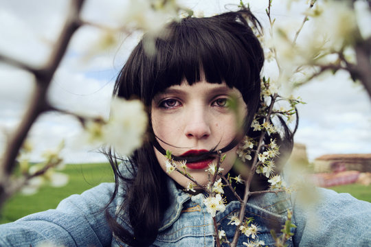 Retrato de una chica joven, morena, con chaqueta vaquera entre flores blancas en el campo 