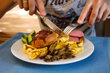 young man eating his breakfast with fork and knife