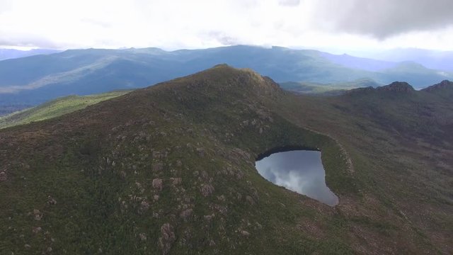 Round pan across majestic mountains revealing Lake Perry at Hartz Mountains National Park, Tasmania, Australia