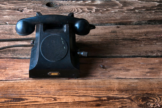 Old-fashioned landline telephone on dark wooden background