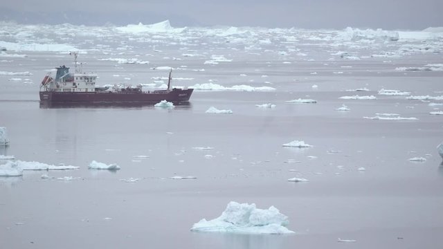ship driving between big icebergs on arctic ocean
